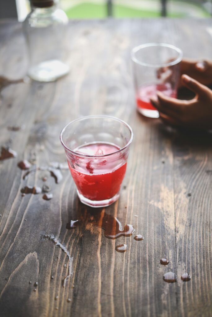 Glas rode kombucha met veel gemors er omheen